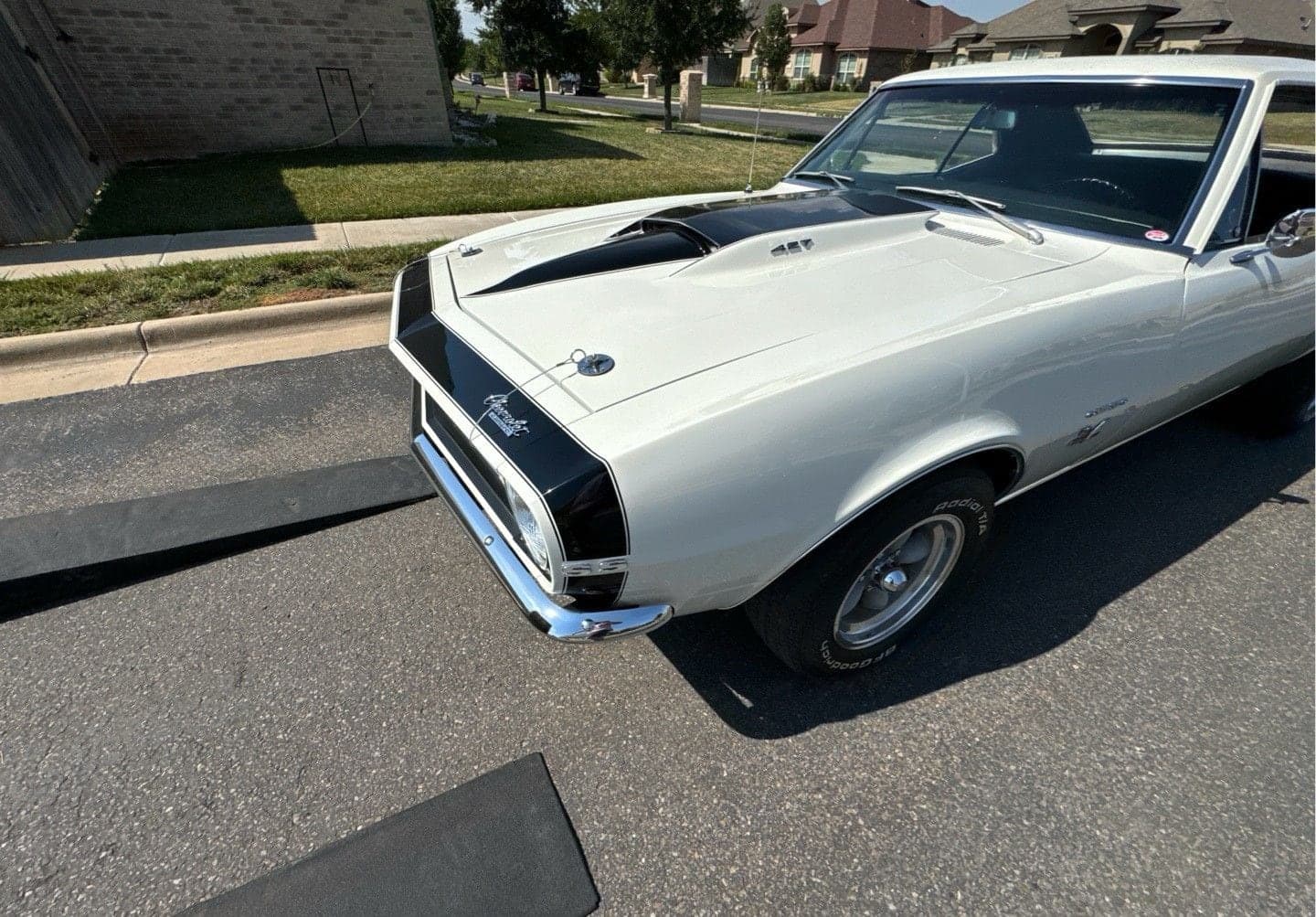 White 1967 Chevrolet Camaro SS with black stripes on a residential street, seen from the front quarter