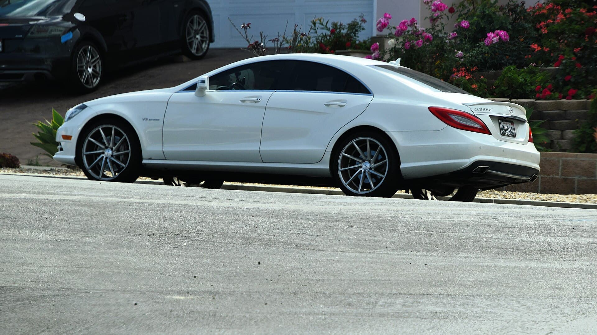 White 2014 Mercedes-Benz CLS 550 parked on a hillside street, side view