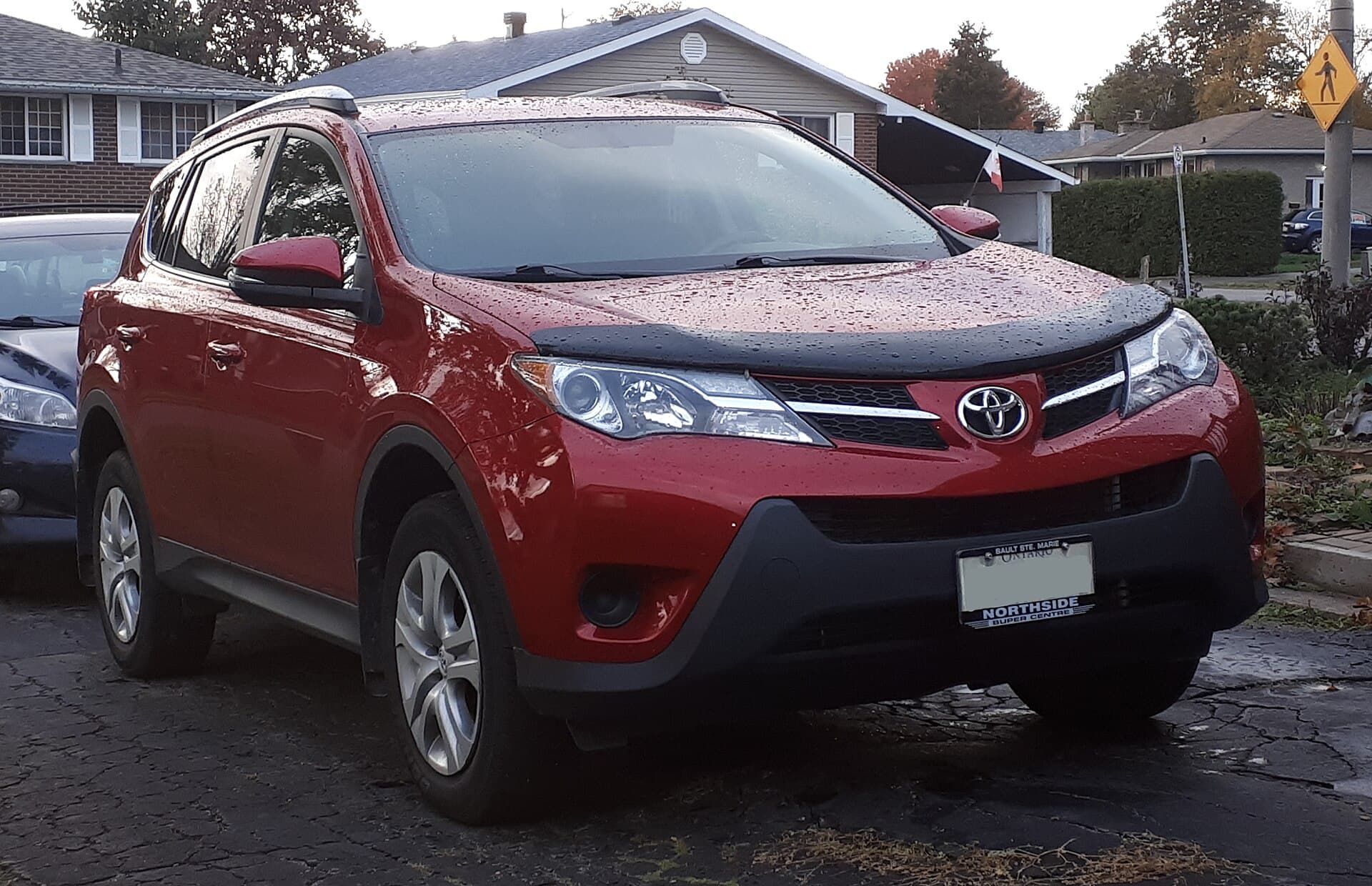 Red 2015 Toyota RAV4 LE on a wet driveway, seen from the front