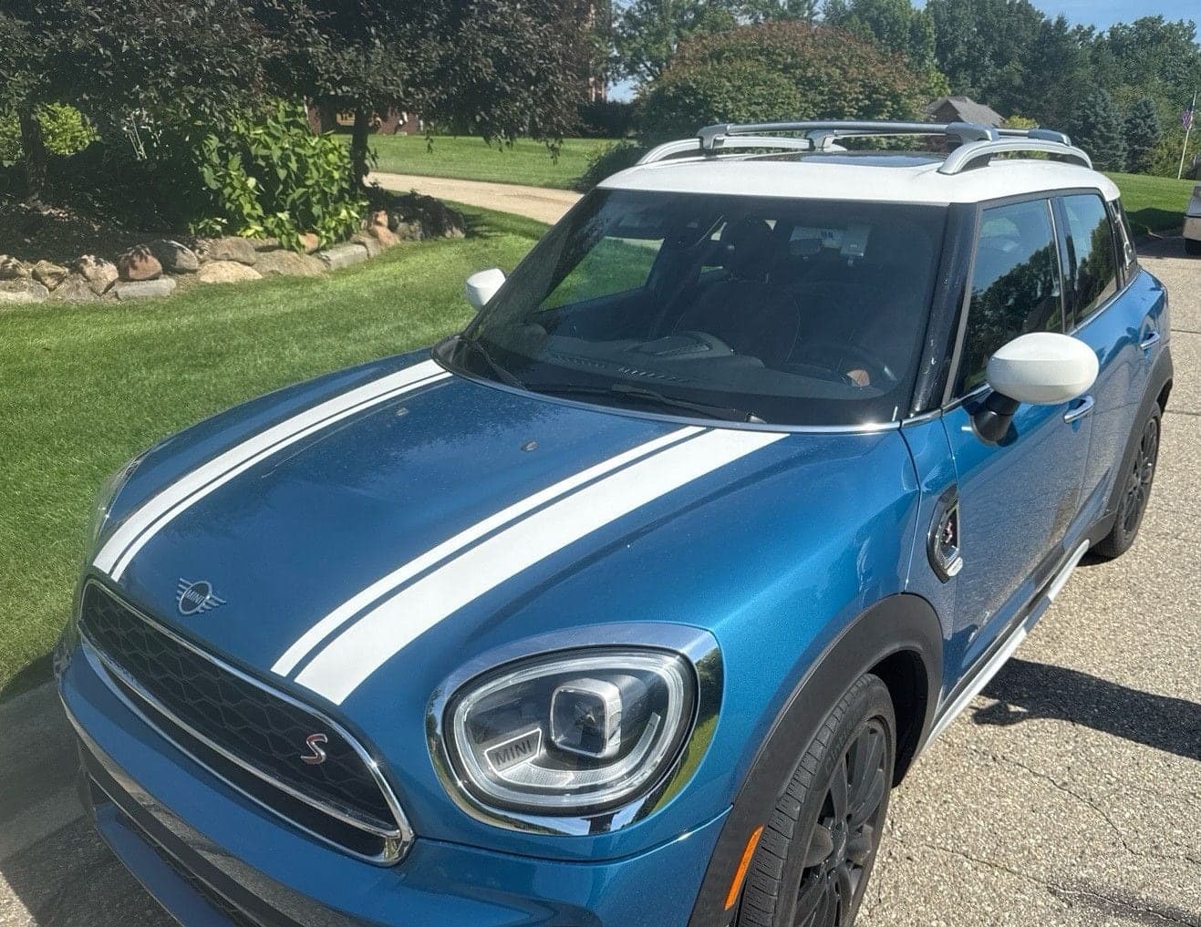 Blue Mini Cooper S Countryman with a white roof and bonnet stripes in a driveway, seen from the front quarter
