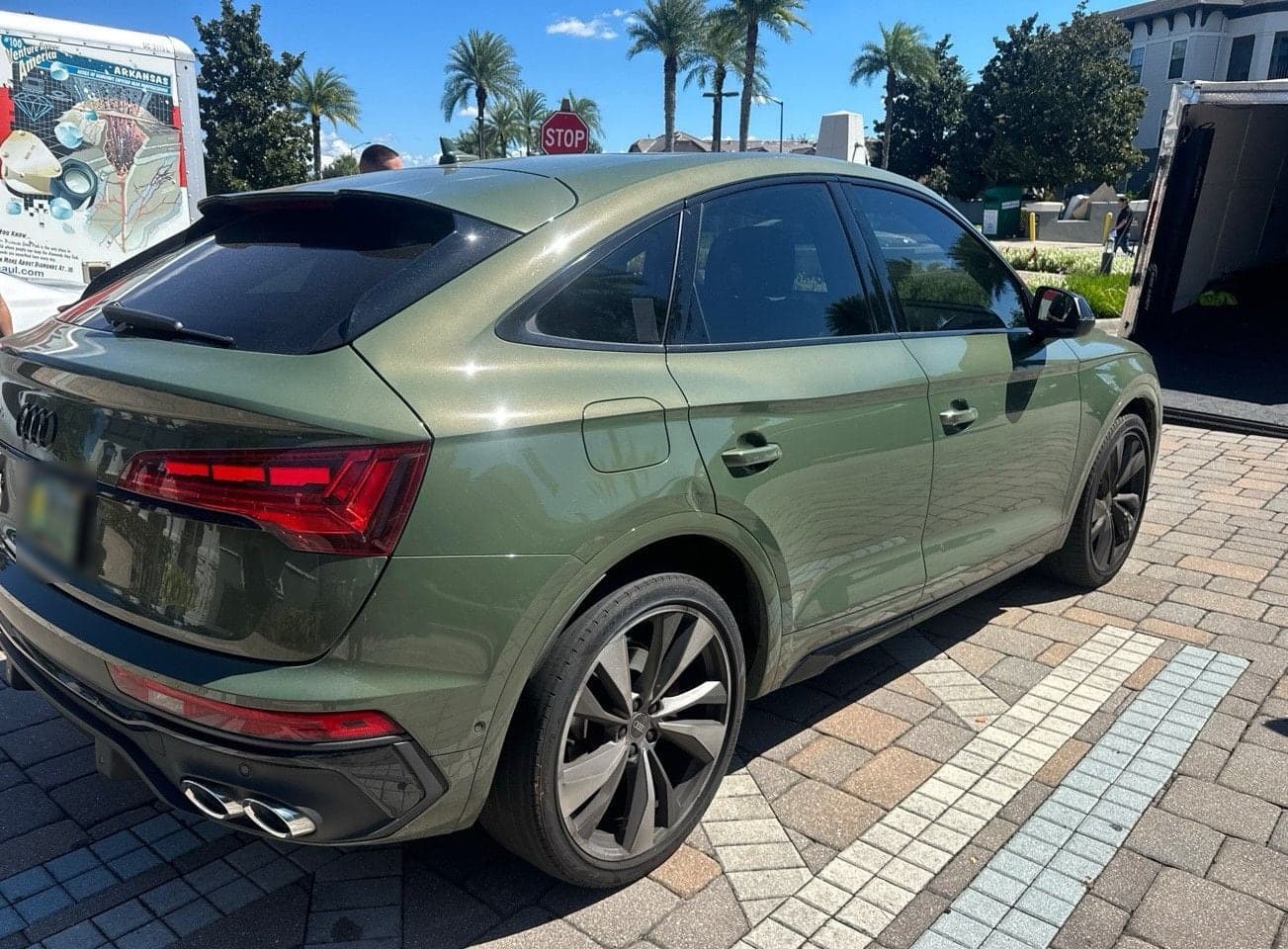 Dark green Audi Q5 seen from the rear quarter, with a car carrier parked behind it