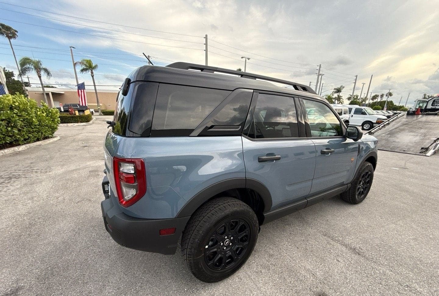 Blue-grey Ford Bronco Sport next to the loading ramp of a car carrier, seen from the rear quarter